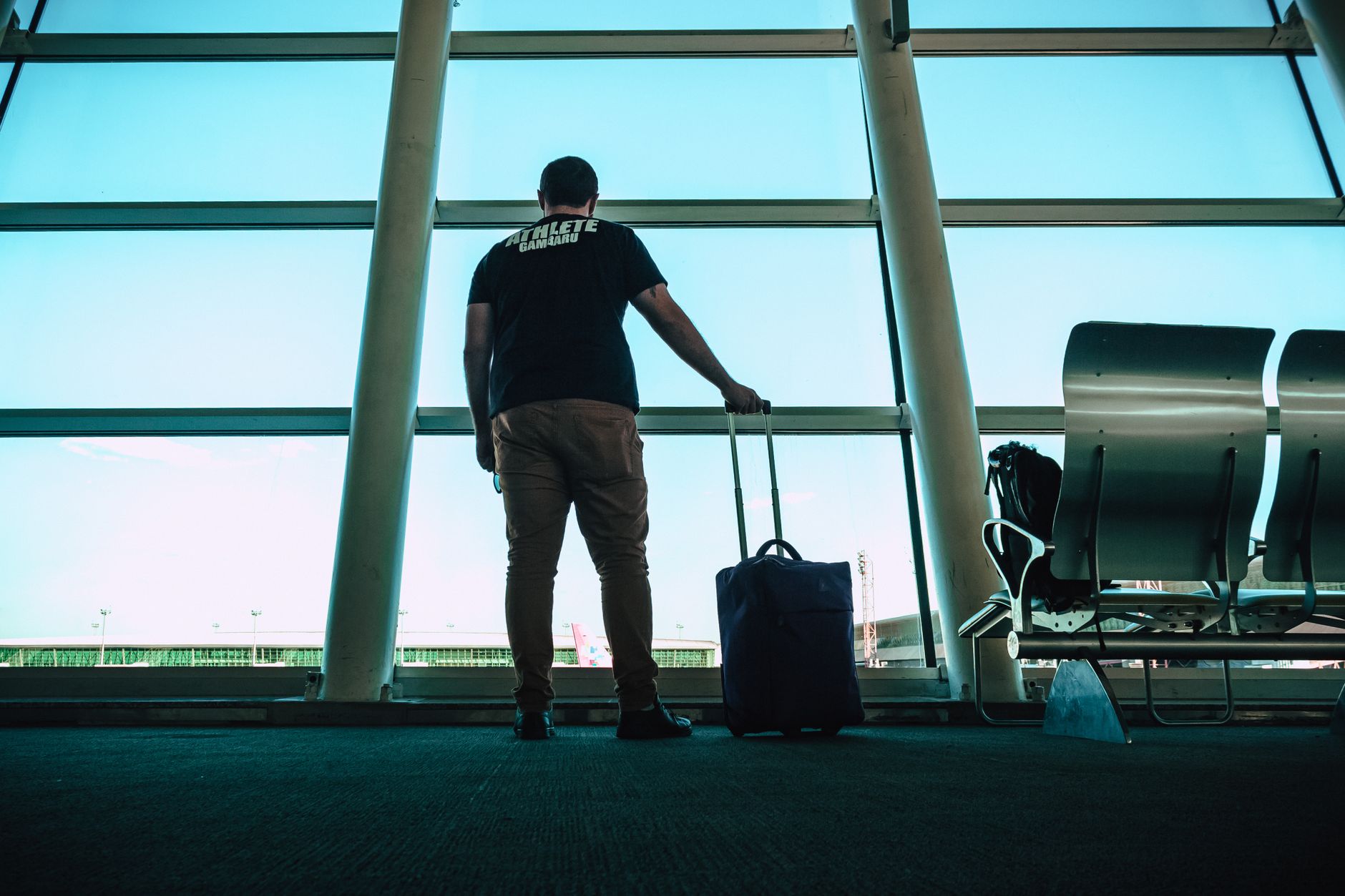 US traveler with a single suitcase at a departure gate flying one-way to the United Kingdom
